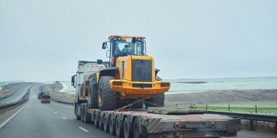 Heavy machinery being transported on a large truck trailer on a highway.