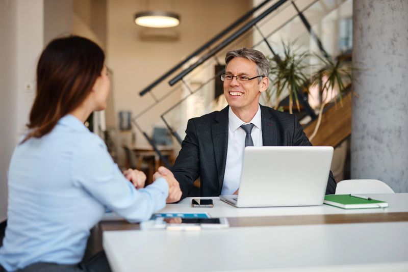 Business partners shaking hands at modern office during a meeting, making business together, closing a deal, hiring process, good news, success, cooperation concept