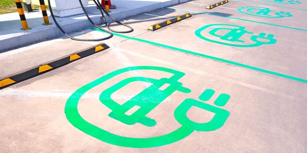 Empty electric vehicle charging stations with green plug symbols on the ground.
