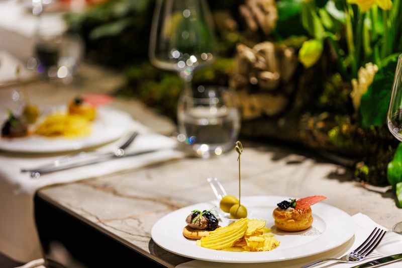 Elegant gourmet appetizers served on white porcelain, featuring puff pastry with black caviar, premium olives, and sophisticated canape bites, ideal for luxury catering and fine dining events.