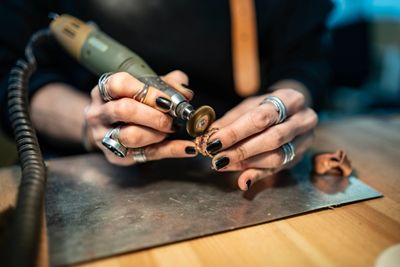 Person using a rotary tool for detailed crafting work.