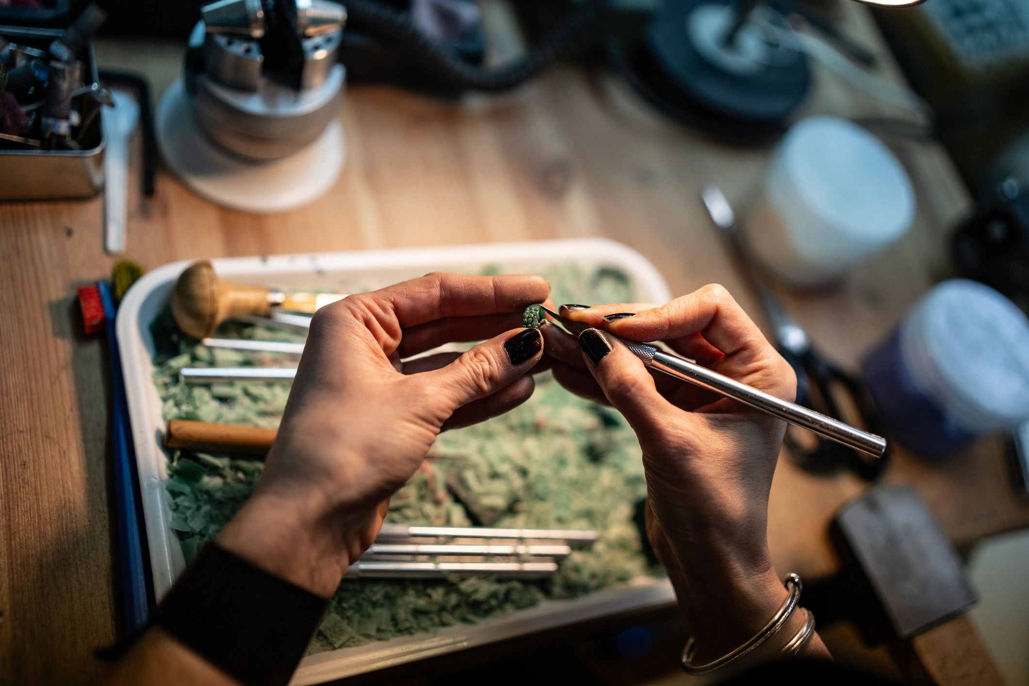 Hands meticulously sculpting a small object with precision tools.
