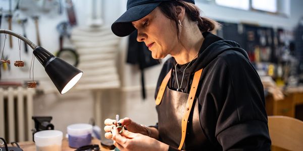A jeweler crafting a ring under focused lighting in a workshop.