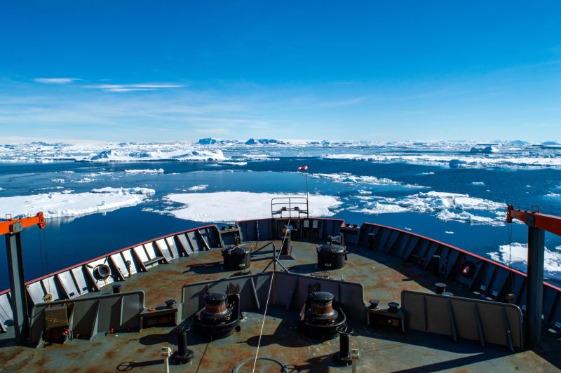A rugged icebreaker ship forces its way through thick Antarctic ice, its reinforced bow splitting frozen sheets under an overcast sky. The dramatic scene highlights the vessel’s role in polar research, supply missions, or climate studies, with icy debris and a vast, desolate landscape in the background. This striking image symbolizes both human engineering and environmental fragility, ideal for themes like global warming, Arctic logistics, or extreme maritime operations.