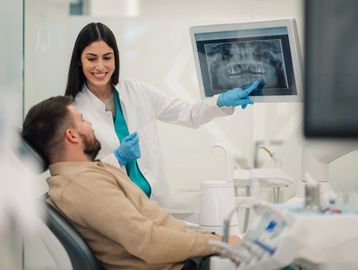 Dentist showing dental x-ray to patient.