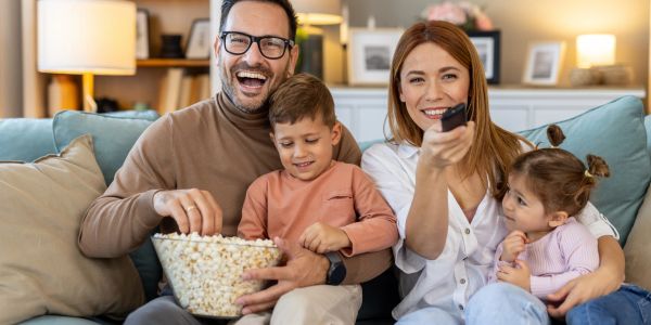 Famille heureuse regardant la télévision avec du pop-corn.