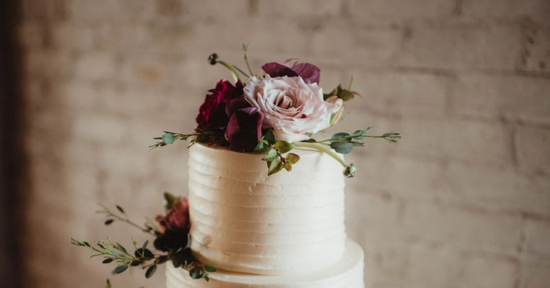 Elegant white cake topped with fresh roses and greenery.