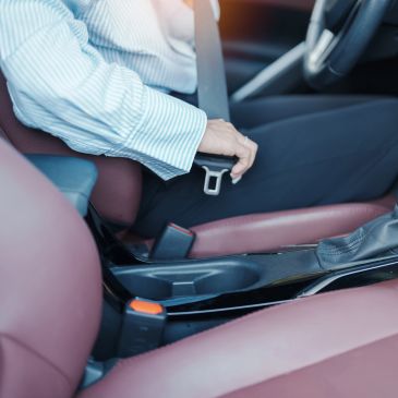Person fastening seatbelt in car.