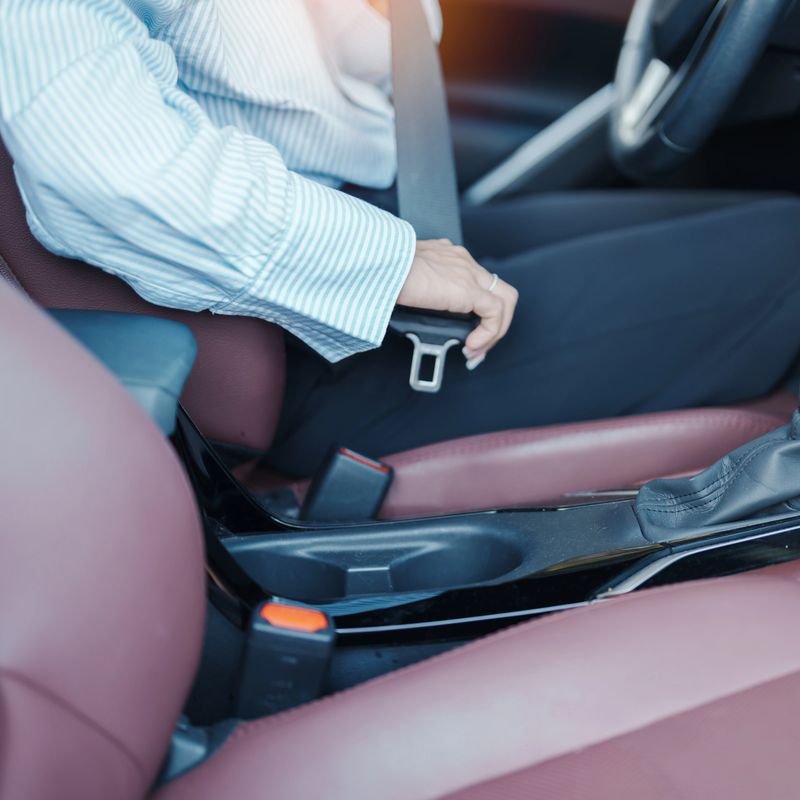 Business woman driver hand fastening seat belt during sitting inside a car and driving in the road. safety, trip, journey and transport concept