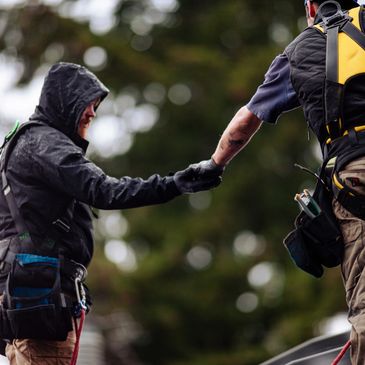 Two climbers shaking hands during a mountain ascent.
