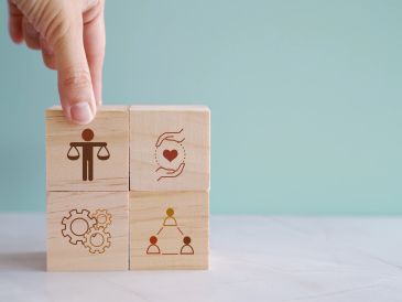 Hand holding wooden blocks with social justice icons.