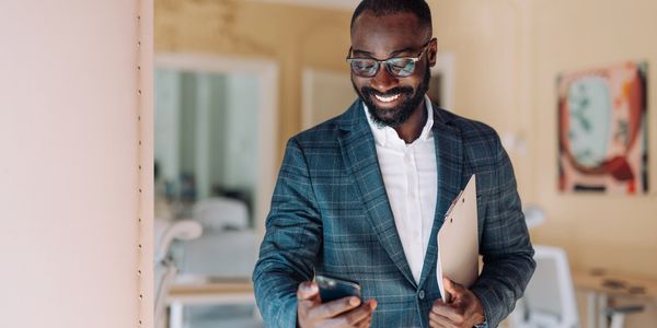 Person smiling and holding a phone at the doorway, ready to welcome clients to their new home.