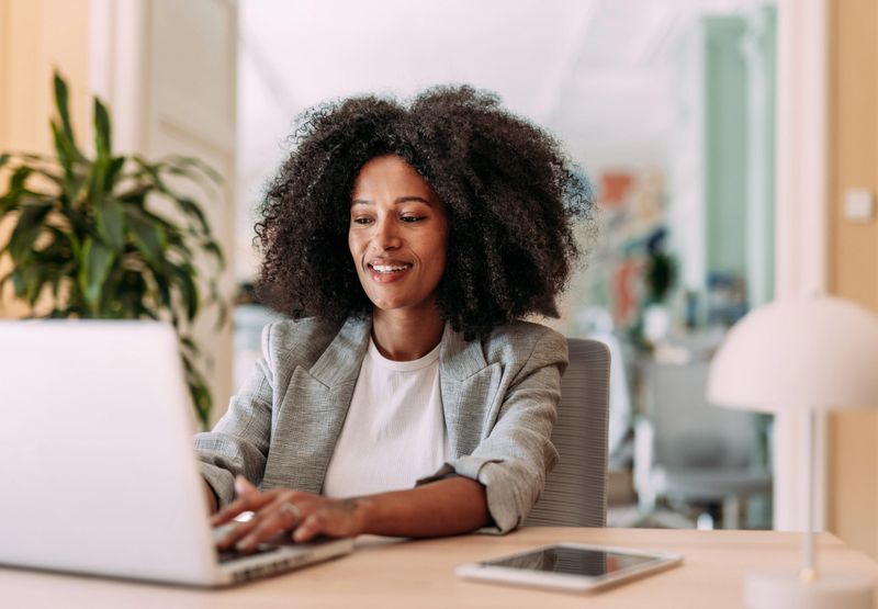 Elegant businesswoman sitting in her office and using laptop.
