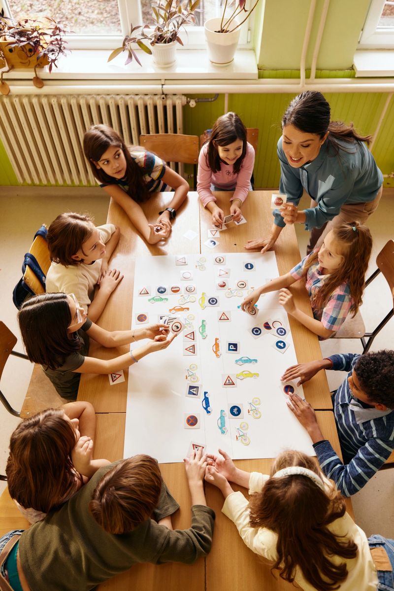 High angle view of happy teacher teaching her elementary students about the traffic and road signs in the classroom.