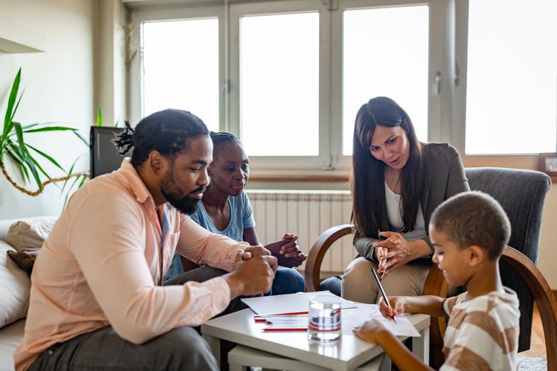 Diverse family receiving counseling from a professional therapist in a cozy living room setting.