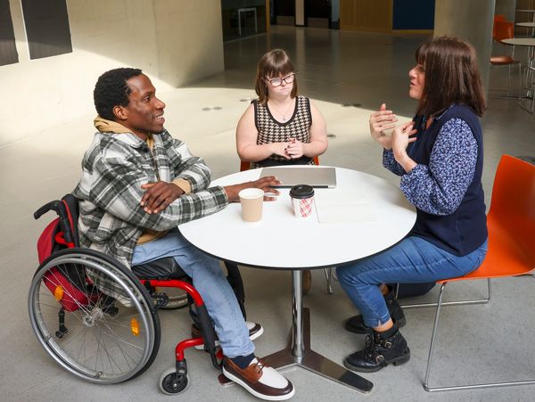 Three people having a discussion at a round table.