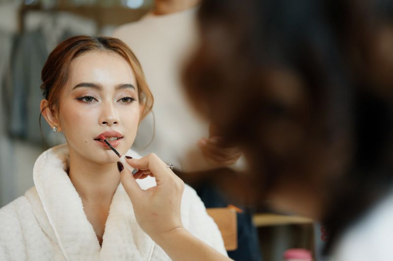 Beautiful bride prepares for her wedding with professional makeup artist and hairstylist.