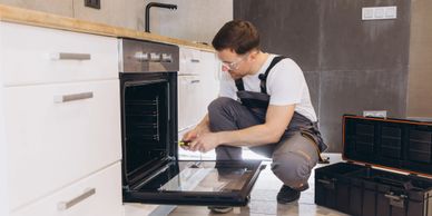 A technician inspecting an open oven in a modern kitchen.