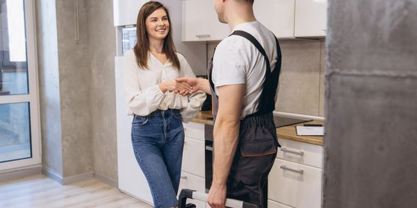 Woman shaking hands with a repairman in a kitchen.