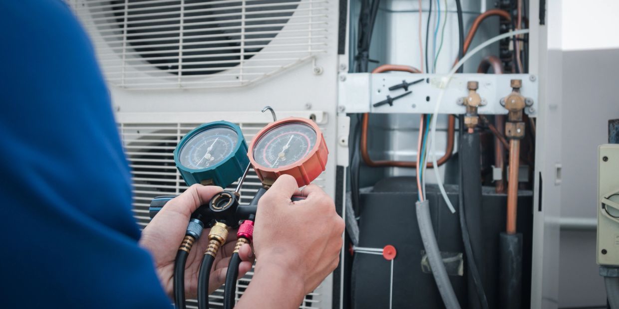 Technician checking HVAC pressure gauges during maintenance.