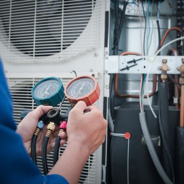 Technician checking HVAC system gauges for pressure and performance.