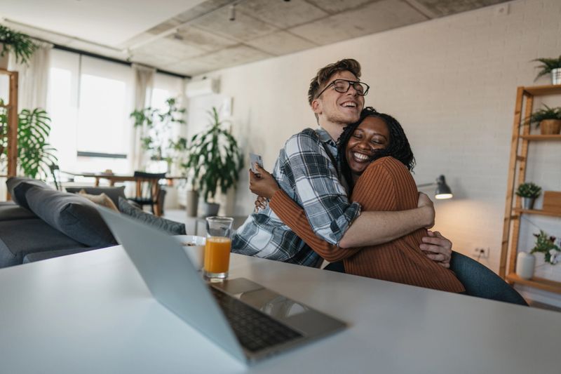 A couple shares a warm embrace in their workspace, radiating happiness and support for one another, emphasizing the importance of love and partnership in a productive environment.
