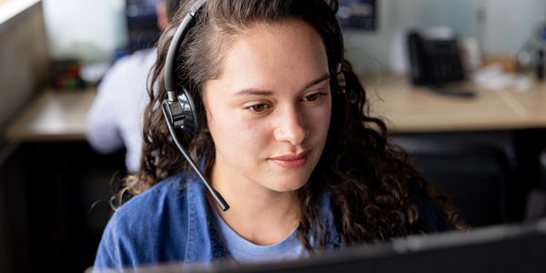 Woman with headset working at a computer.