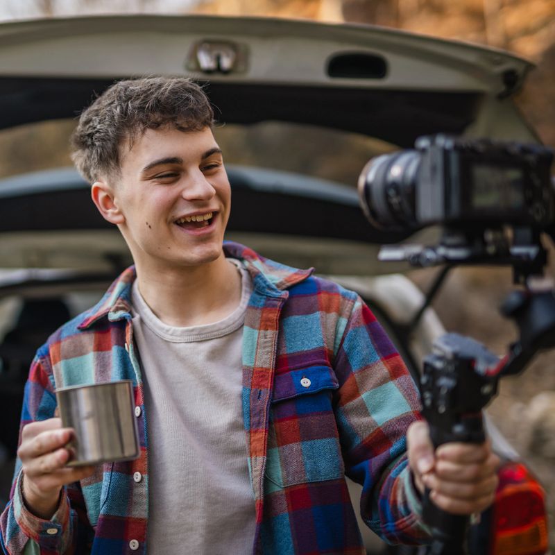 Man hiker video maker making video on camera with stabilizer in front car tanker. Video content creation concept.