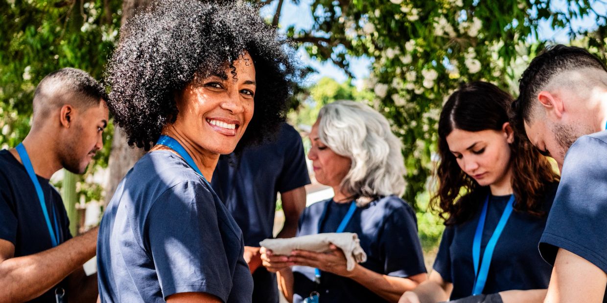 Group of diverse volunteers outdoors, smiling and working together.