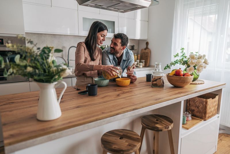 Young smiling couple preparing breakfast together in their modern kitchen, enjoying each other's company and starting their day with a healthy meal