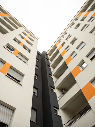 Low-angle view of modern apartment buildings with white, black, and orange accents.