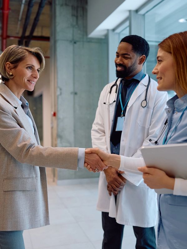 A patient shaking hands with a female doctor while a male doctor observes.