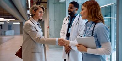 Patient shaking hands with healthcare professionals in a hospital corridor.