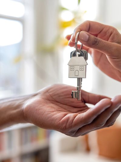 Handing over house keys symbolizing home ownership or real estate transaction.