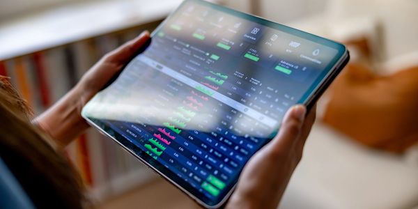 Person holding a tablet displaying financial stock market data with charts and figures.