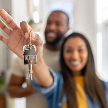 Happy couple holding house keys, celebrating new home ownership.
