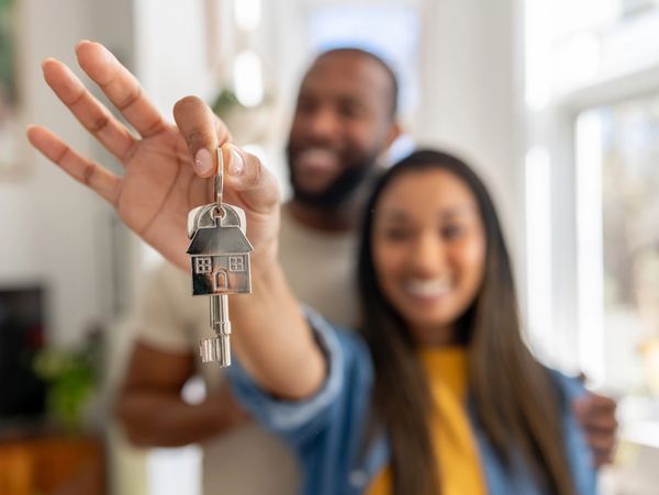 Happy couple holding house keys, celebrating new home ownership.