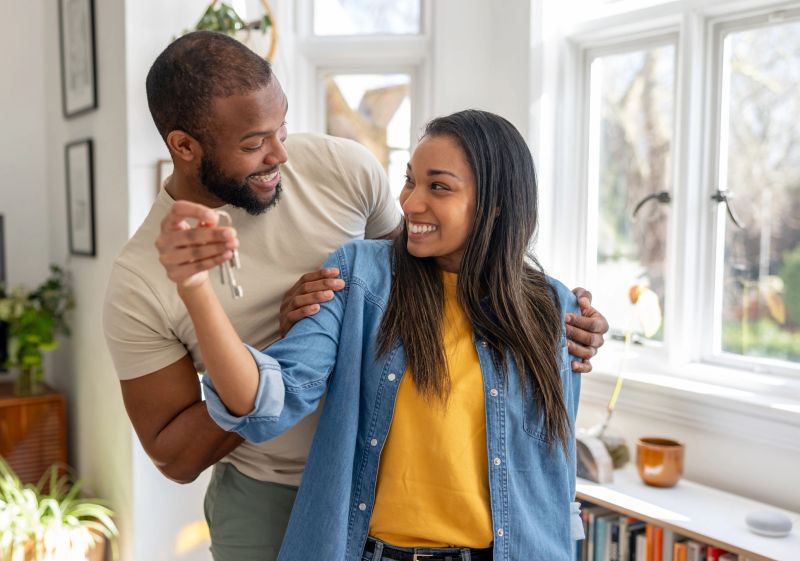 Loving African American couple looking very happy holding the keys of their new house - home ownership concepts