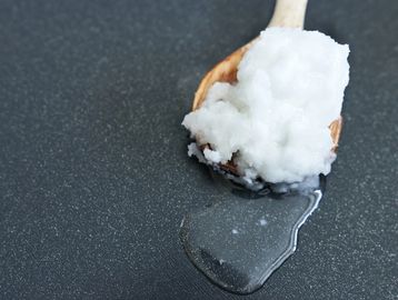 coconut wax in a wooden spoon melting onto a table