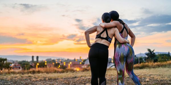 Two women embracing while enjoying a sunset outdoors.
