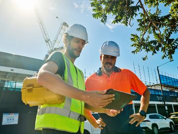 Two construction workers reviewing plans outdoors.