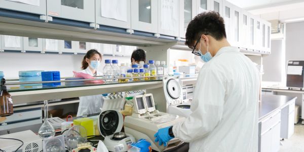 Scientists working in a lab wearing masks and gloves.