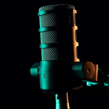 Close-up of a studio microphone with dramatic lighting against a black background.