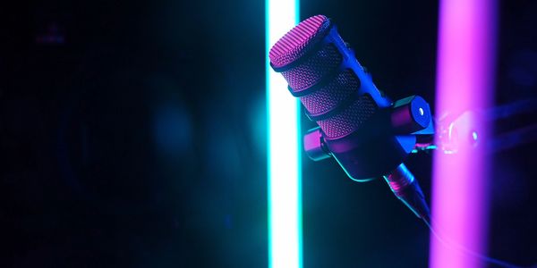 Close-up of a microphone with blue and pink neon lights in the background.