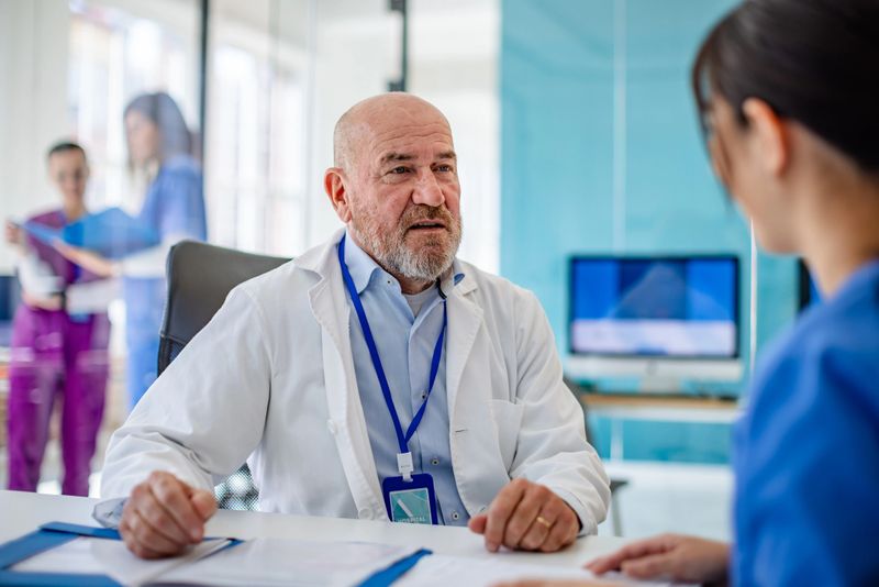 In a modern hospital, healthcare professionals, including a doctor and nurse, engage in a detailed discussion about patient care strategies, enhancing collaboration and planning.