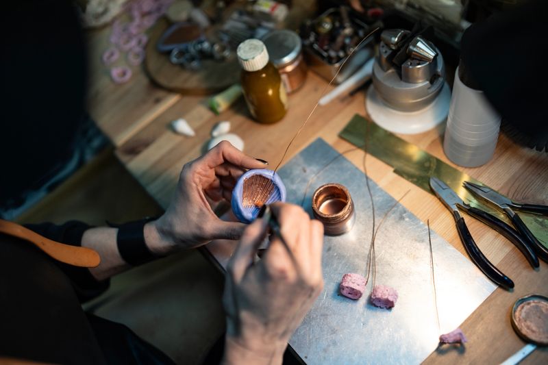 Artisan carefully crafting a unique wire and resin piece in a detailed workshop environment with various tools and materials neatly arranged, showcasing dedication and precision.