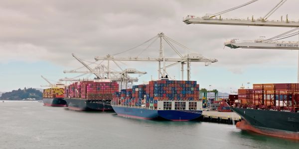Container ships docked at a port with cranes.
