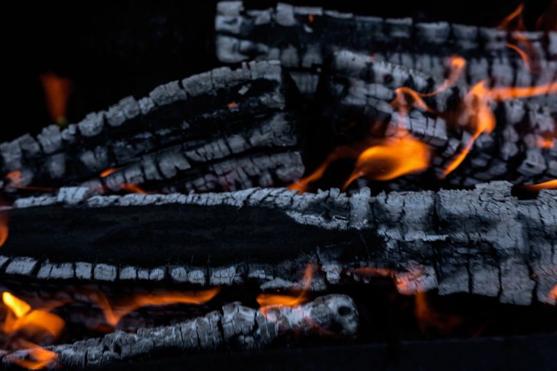Burning wood on the grill for further cooking meat over coals