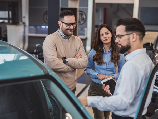 People inspecting a car at a dealership.