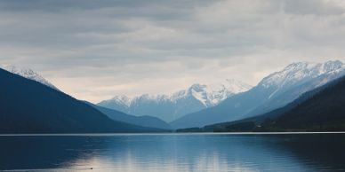 A serene landscape with mountains, a lake, and a clear blue sky.